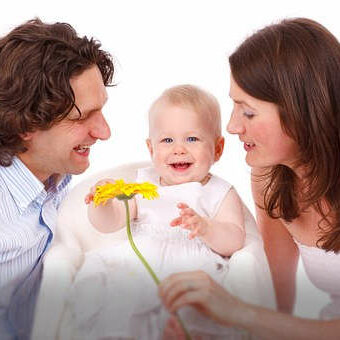 Eltern mit Kind, das lacht und eine gelbe Blume anfasst