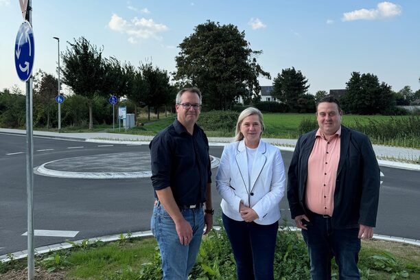 Bürgermeisterin Susanne Stupp präsentiert die sanierte Fahrbahn und den neuen Kreisverkehr an der Augustinusstraße gemeinsam mit den städtischen Bauverantwortlichen Christian Lessenich (Abteilungsleiter Verkehrsmanagement) und André Kurth (Sachbearbeiter).