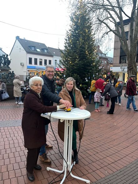 (v.l.n.r.) Aktivkreis-Mitglied Marianna Carrié, Sponsor Volker Frank und Bürgermeisterin Susanne Stupp vor dem Weihnachtsbaum am Klüttenbrunnen