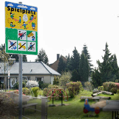 Das Foto zeigt eine Spielplatzfläche in Frechen. Es ist ein Schild aufgestellt mit dem Hinweis Spielplatz.