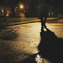 Bild zeigt Person, die in der Dunkelheit eine Straße entlang geht
