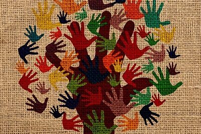 Das Bild zeigt verschiedenfarbige Hände auf Leinen gedruckt, die zusammen einen Baum bilden.